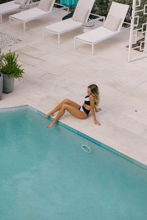 Sleek swimming pool deck with white lounge chairs and turquoise water at luxury resort.