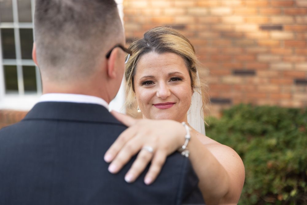 An intimate outdoor wedding moment captured against a red brick backdrop.