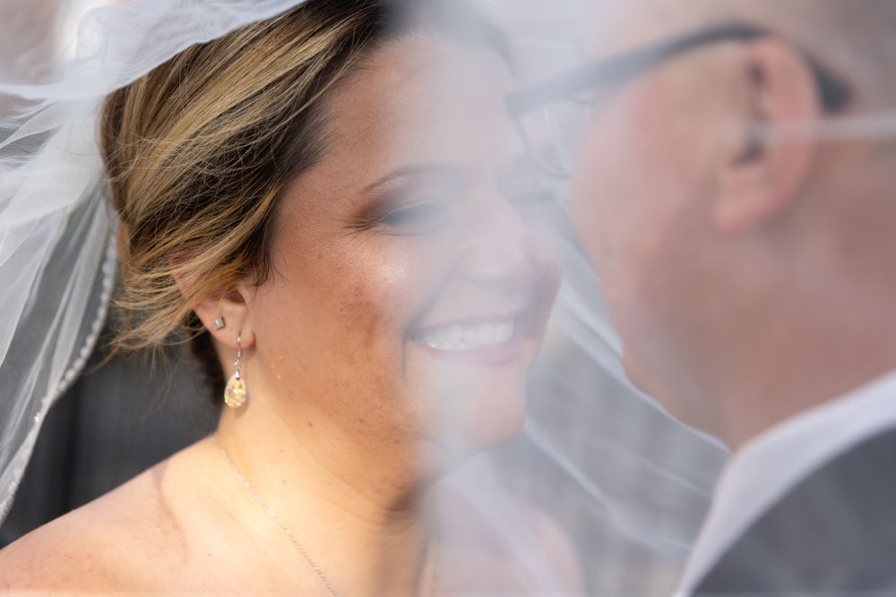 An artistic wedding photo through sheer veil fabric creating a dreamy, romantic effect.