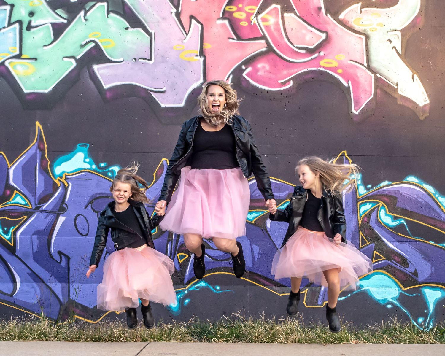 Artistic photos against a vibrant graffiti wall featuring pink tulle skirts.