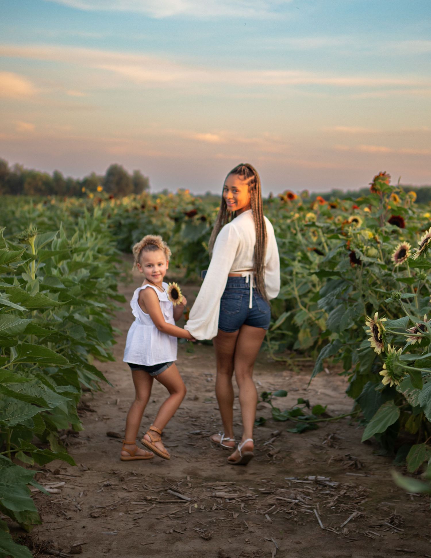 Children playing in a sunflower field during golden hour.