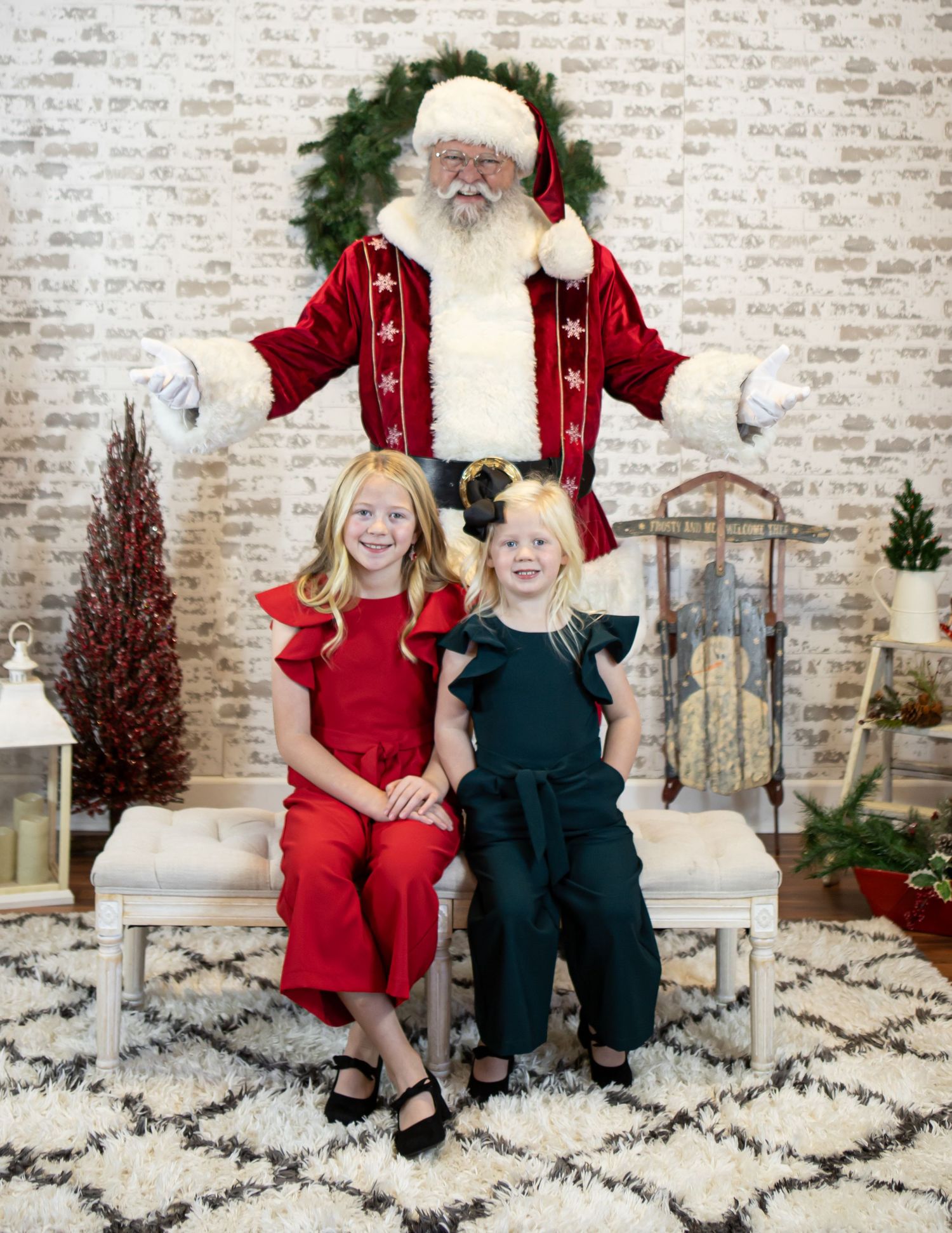 Holiday portrait setup with red and green decor against white brick wall.