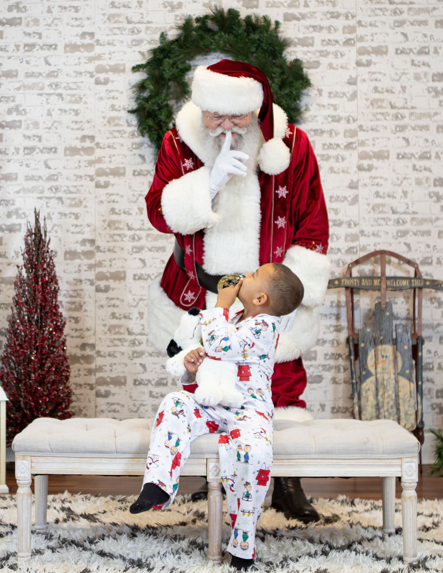 Christmas scene with figure in traditional red suit interacting with child in holiday pajamas.