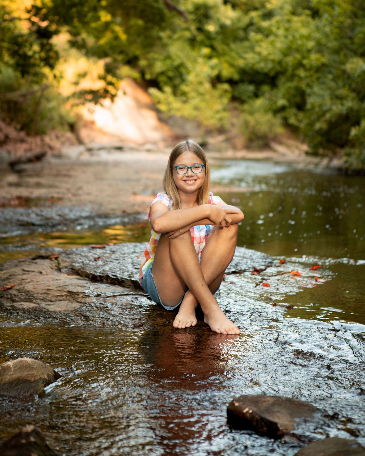 Person enjoying a peaceful moment sitting in a shallow creek during golden hour.