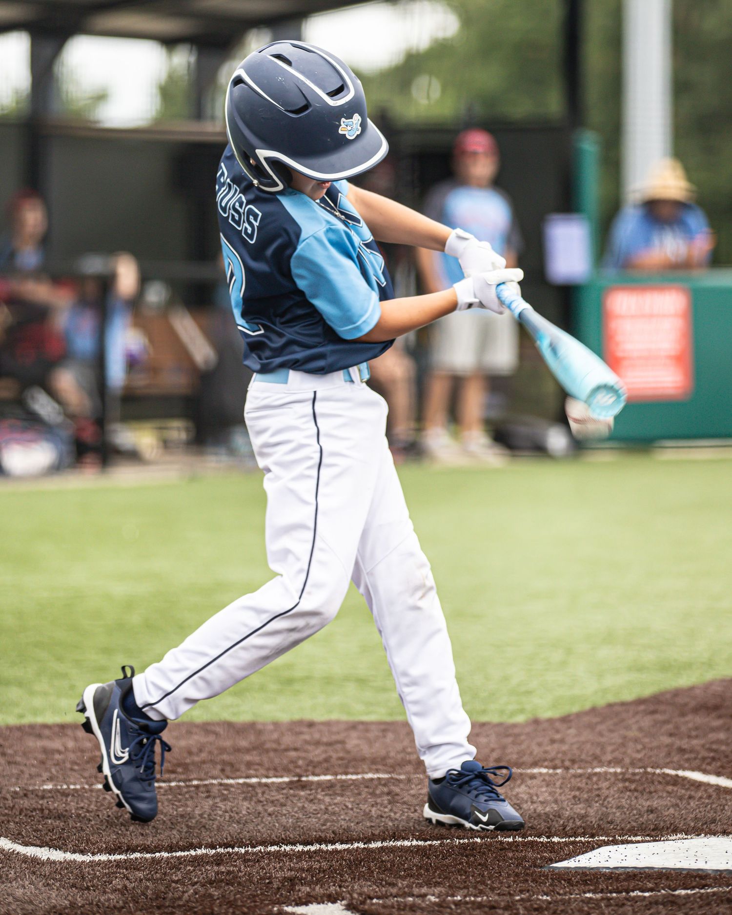 Close-up sequence of baseball batter's stance and swing at home plate during youth baseball game.