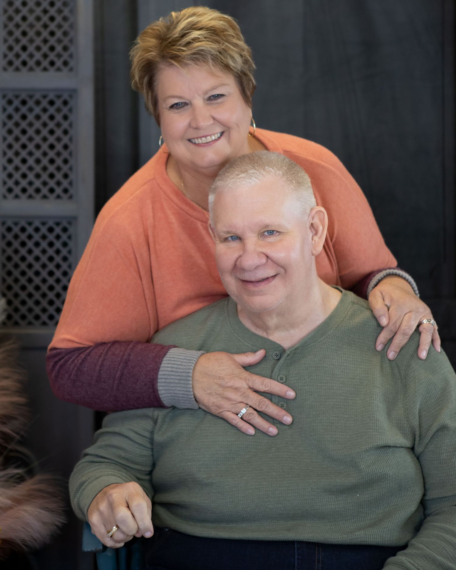 Family portrait with two people wearing orange and olive green sweaters.