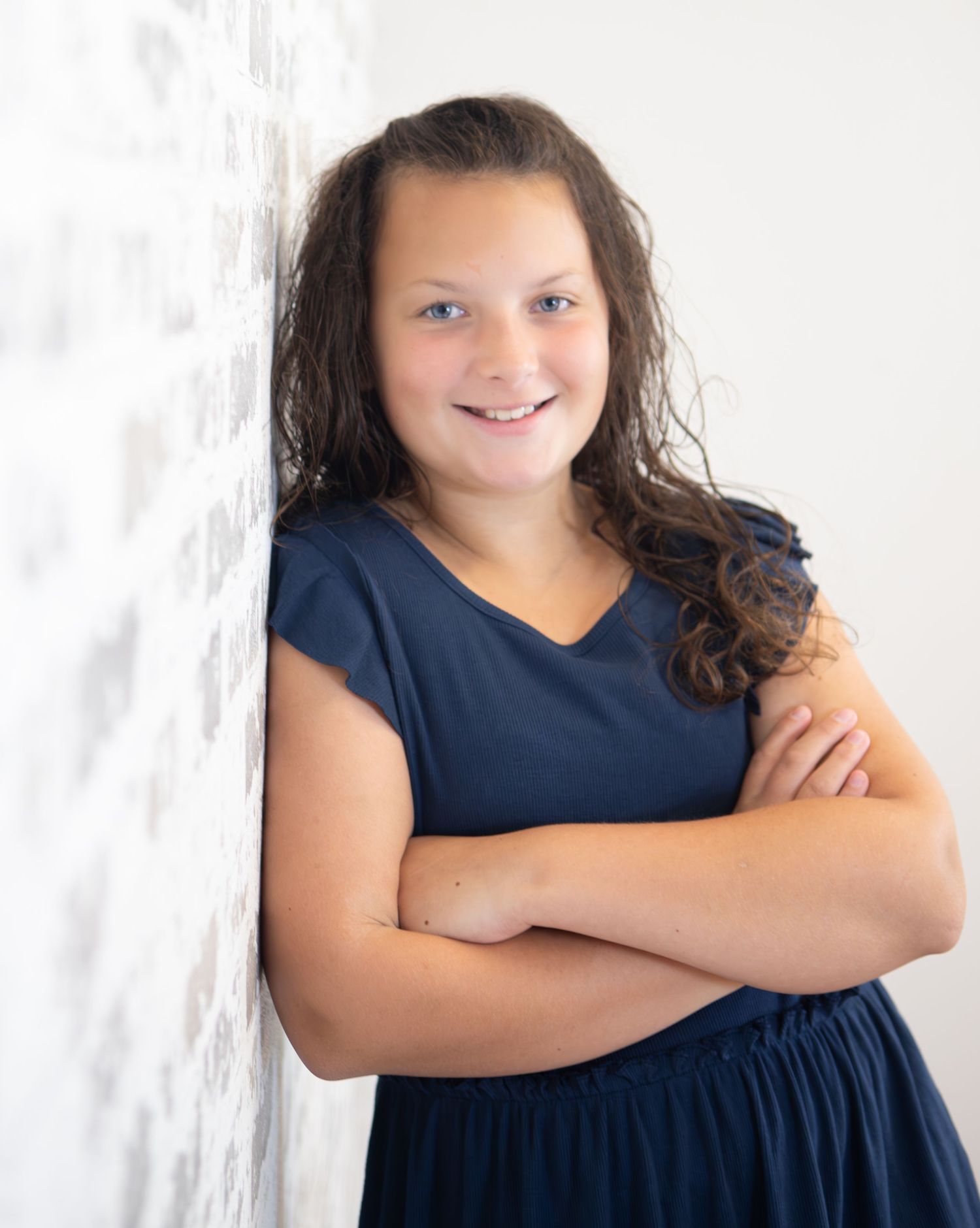 Portrait against white backdrop showing person in navy blue dress.