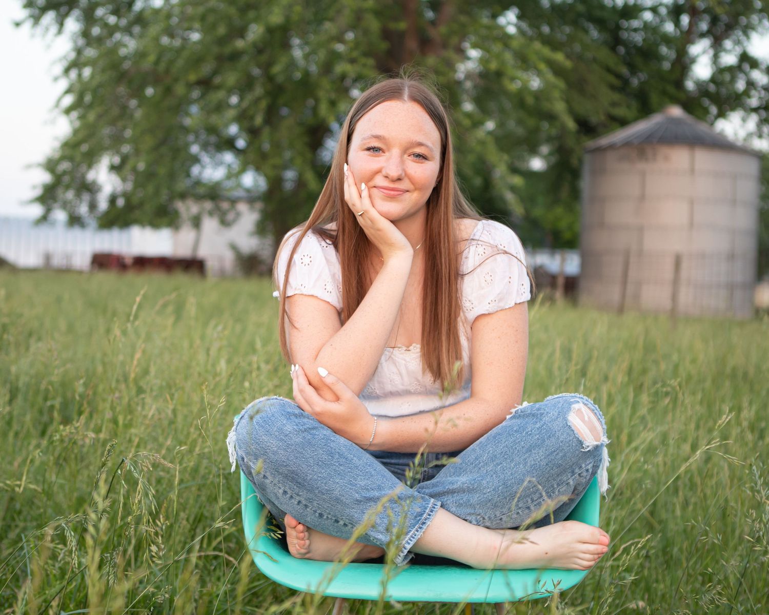 Young woman relaxes on blanket in sunny meadow during outdoor portrait session.