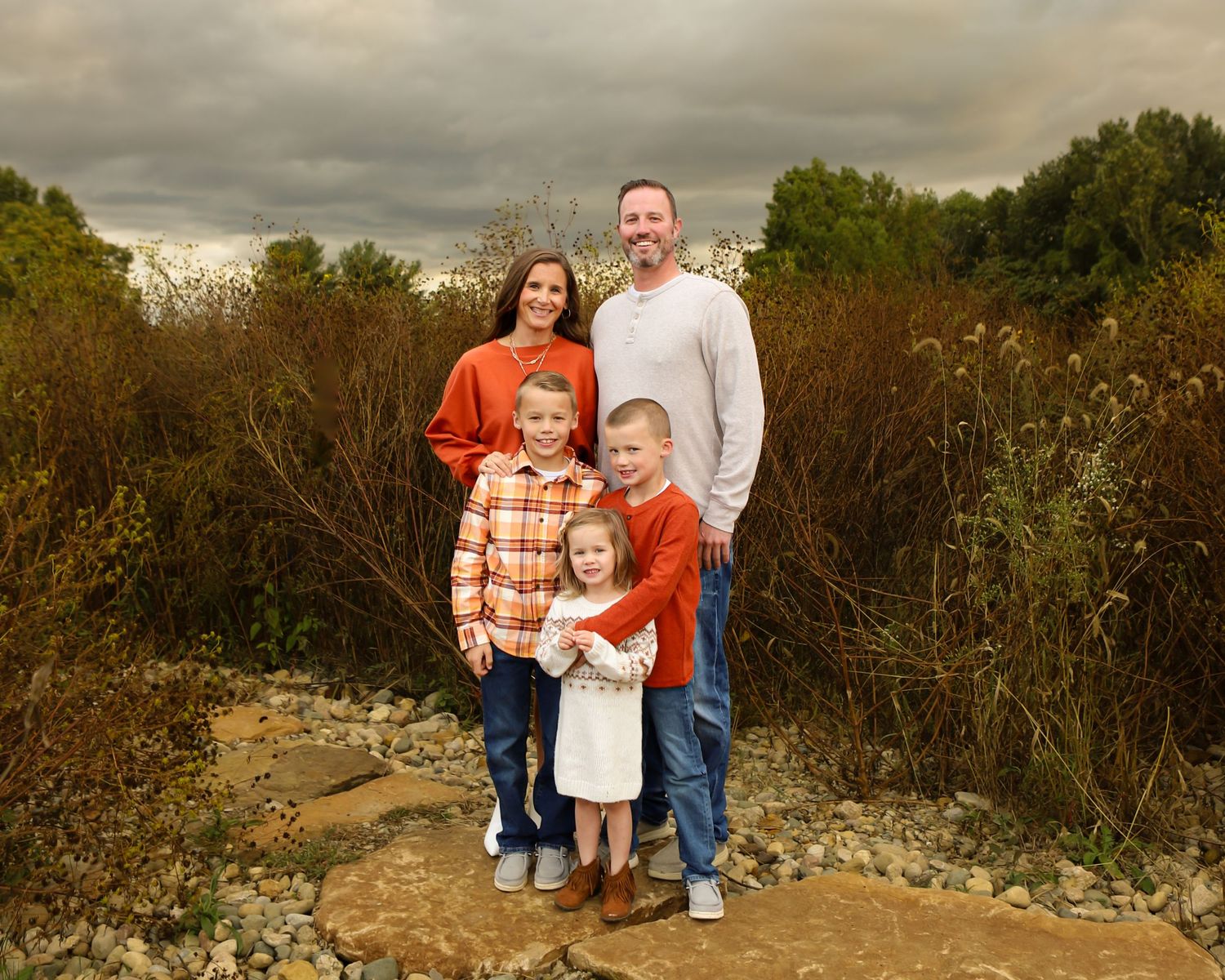 Family photo session in a desert landscape with dramatic cloudy sky at sunset.