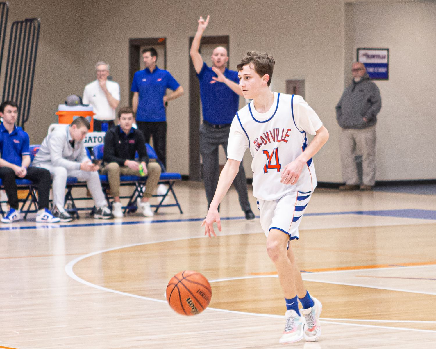Basketball players dribbling and moving across court during competitive game.