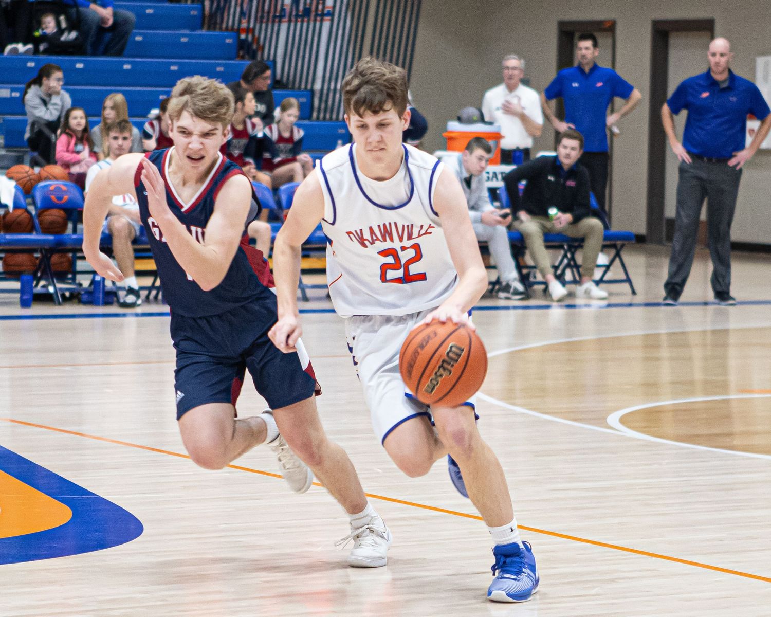 Basketball players in motion on court showing dribbling and defensive positions.