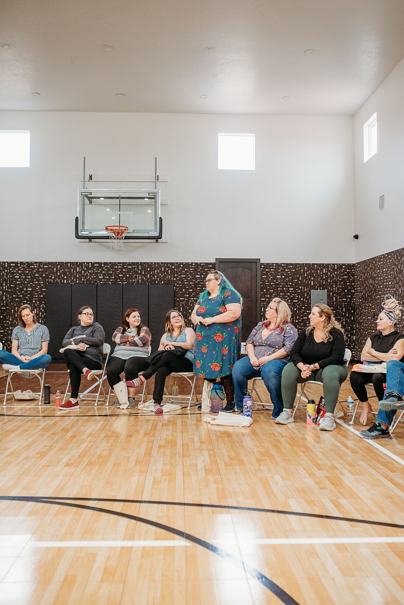 Group therapy or workshop session in gymnasium with basketball hoop.