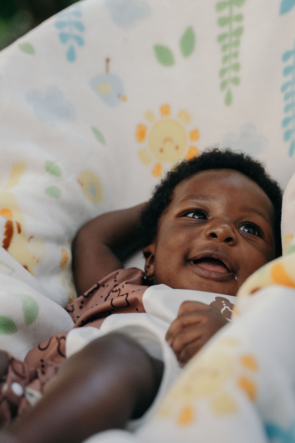 A smiling baby lying on a patterned blanket