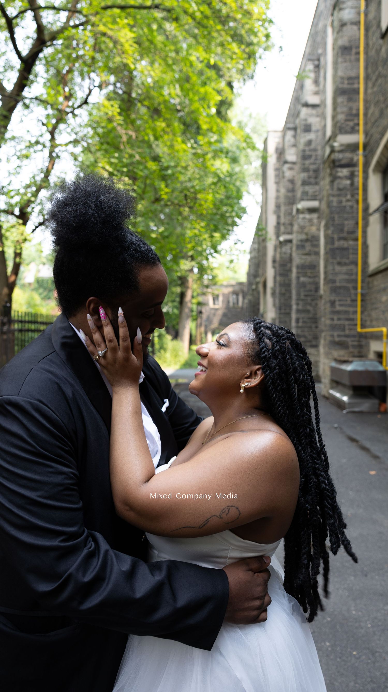Romantic wedding photoshoot moment captured in front of historic stone building.
