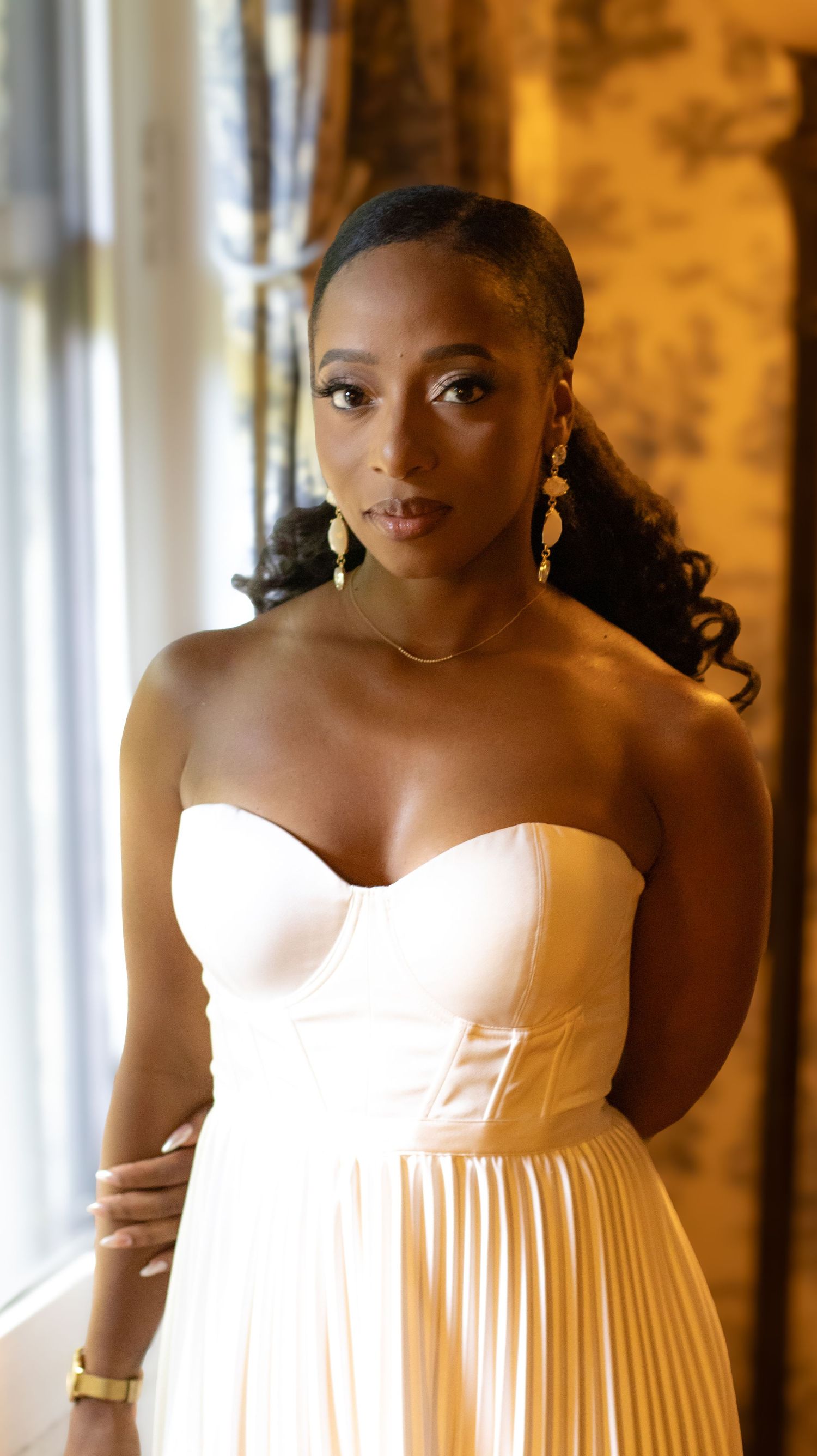 Elegant white pleated wedding dress captured in warm lighting.