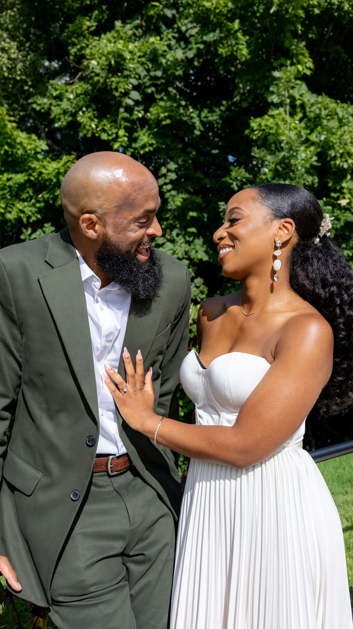 Joyful couple in wedding attire sharing a candid moment outdoors.