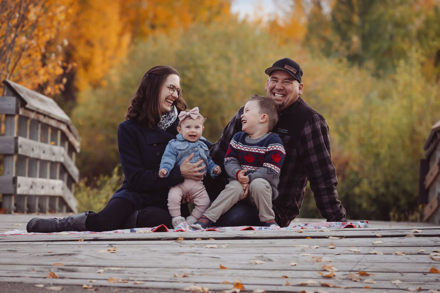 Happy family laughing together on wooden walkway during autumn season.