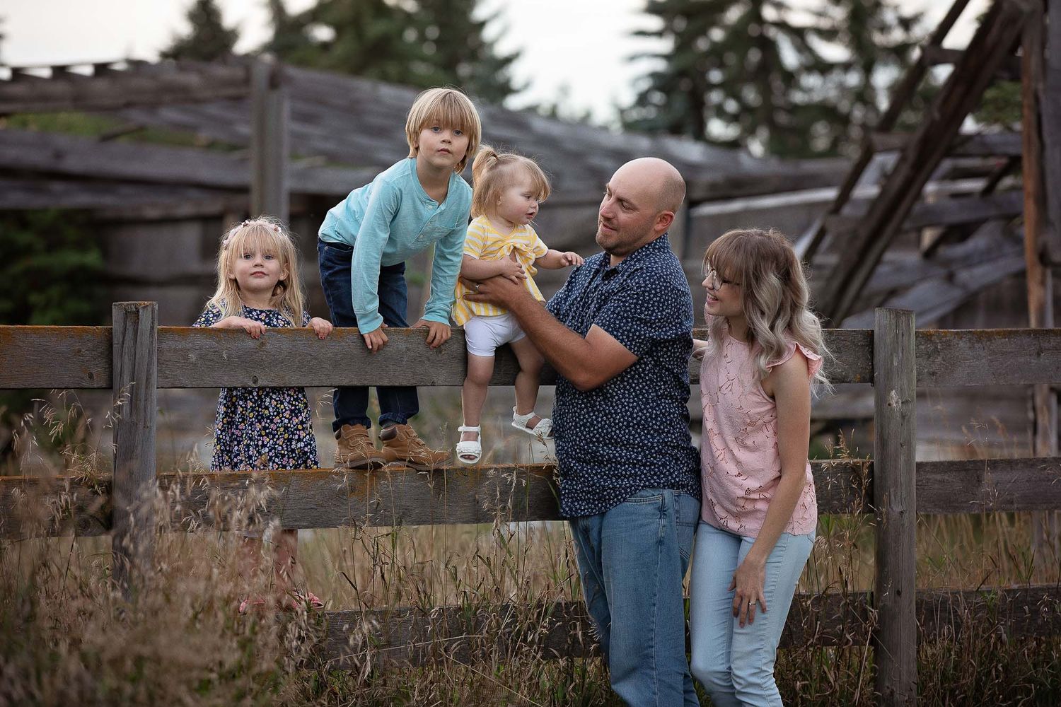 A joyful family moment together outdoors by a rustic wooden fence during golden hour.