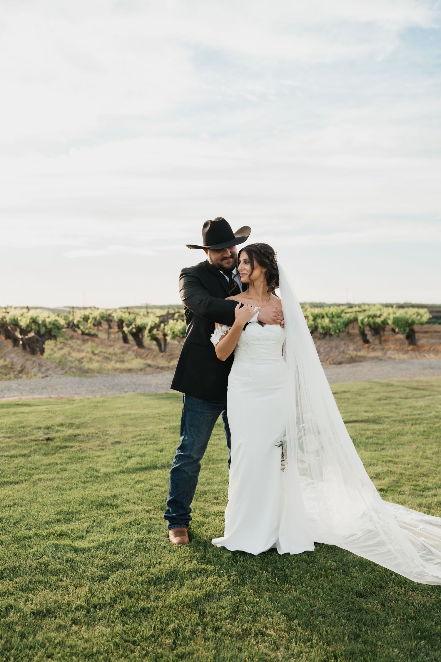 Wedding party laughs together outdoors with bridesmaids in navy dresses and groomsmen in black suits.