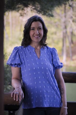 A woman smiling outside with water in the background
