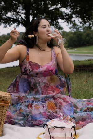 A woman eating birthday cake for a birthday photoshoot outside at a picnic