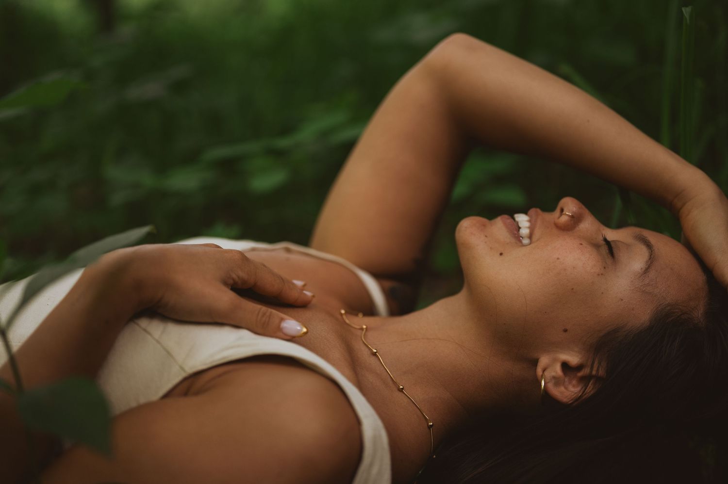 People lying on grassy hillside under cloudy sky.