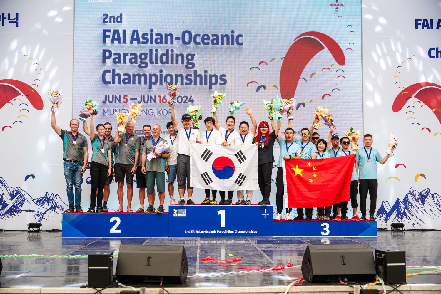 Winners podium at Asian-Oceanic Paragliding Championship with teams displaying flags and medals.