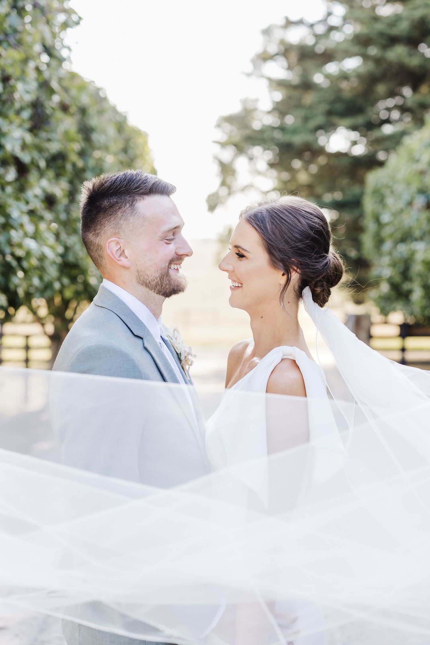 Romantic wedding portrait with flowing veil and soft natural lighting in garden setting.