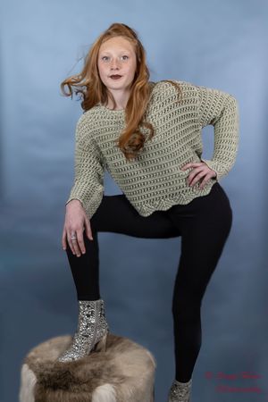 Portrait showcasing a knit sweater and fashion styling against a blue backdrop.