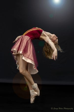 A ballet dancer in pink costume arches backwards under dramatic spotlight. Sonya Helm Equine Photography, Bristol, TN