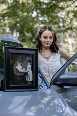 Car photography scene with vintage photo frame displayed on hood of vehicle.
