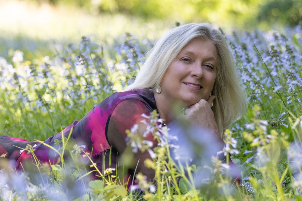 A person lies in a sunny meadow of blooming purple lupine flowers while enjoying a spring day.