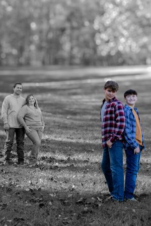 Family photo with color splash effect showing figures standing in an autumn field.