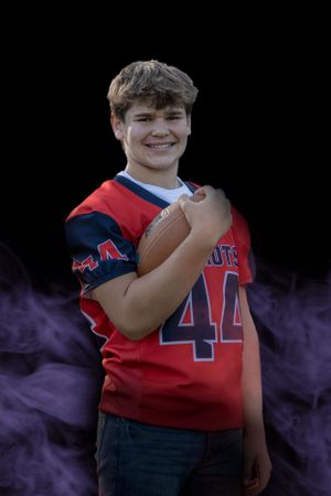 Youth sports portrait with purple smoke effect showing player holding football.