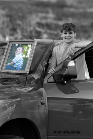 Black and white photo showing vehicle with framed photo on dashboard.