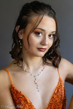 Elegant close-up portrait showcasing crystal jewelry and orange sequined formal dress.