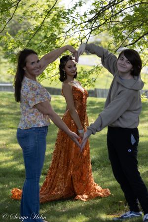Behind-the-scenes photo of outdoor photoshoot with assistants creating heart shape above model.
