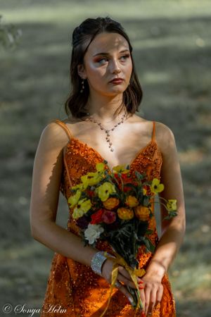 Orange sequined gown paired with colorful autumn bouquet in outdoor portrait.