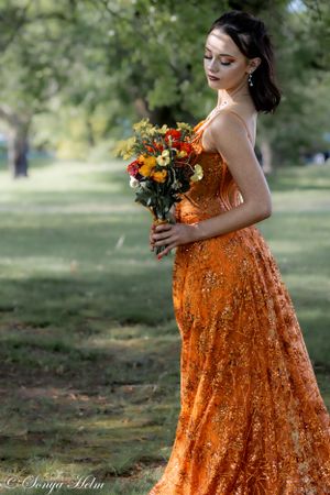 Orange sequined formal dress captured in soft natural lighting with floral bouquet.
