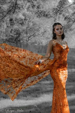 A dramatic orange sequin dress shown in black and white with selective coloring.