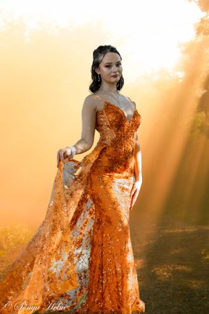 A flowing orange sequined dress photographed during golden hour with dramatic sunbeams.