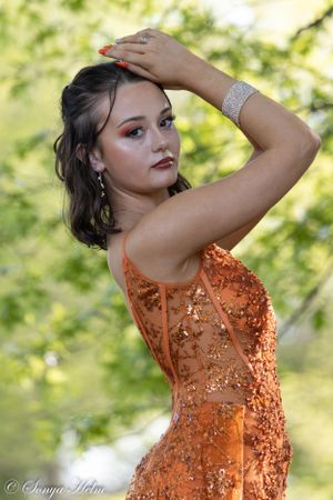 An orange sequined formal dress shimmers in dappled sunlight during an outdoor photo session.