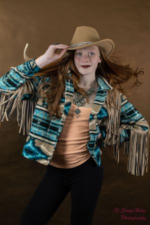 Western-inspired look with fringe jacket, turquoise accessories, and tan cowboy hat.