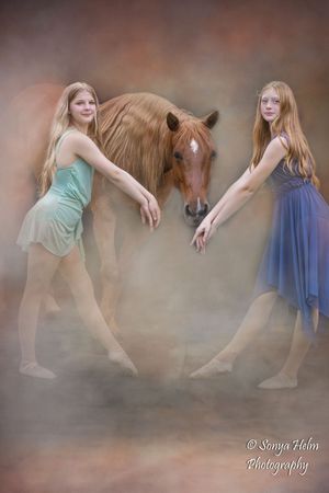 Two dancers in mint and blue dresses perform graceful movements with a horse in a dreamy, misty setting.
