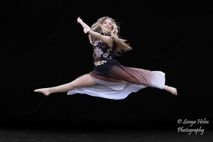 A dancer performing graceful aerial splits against a black backdrop in an artistic photo series.