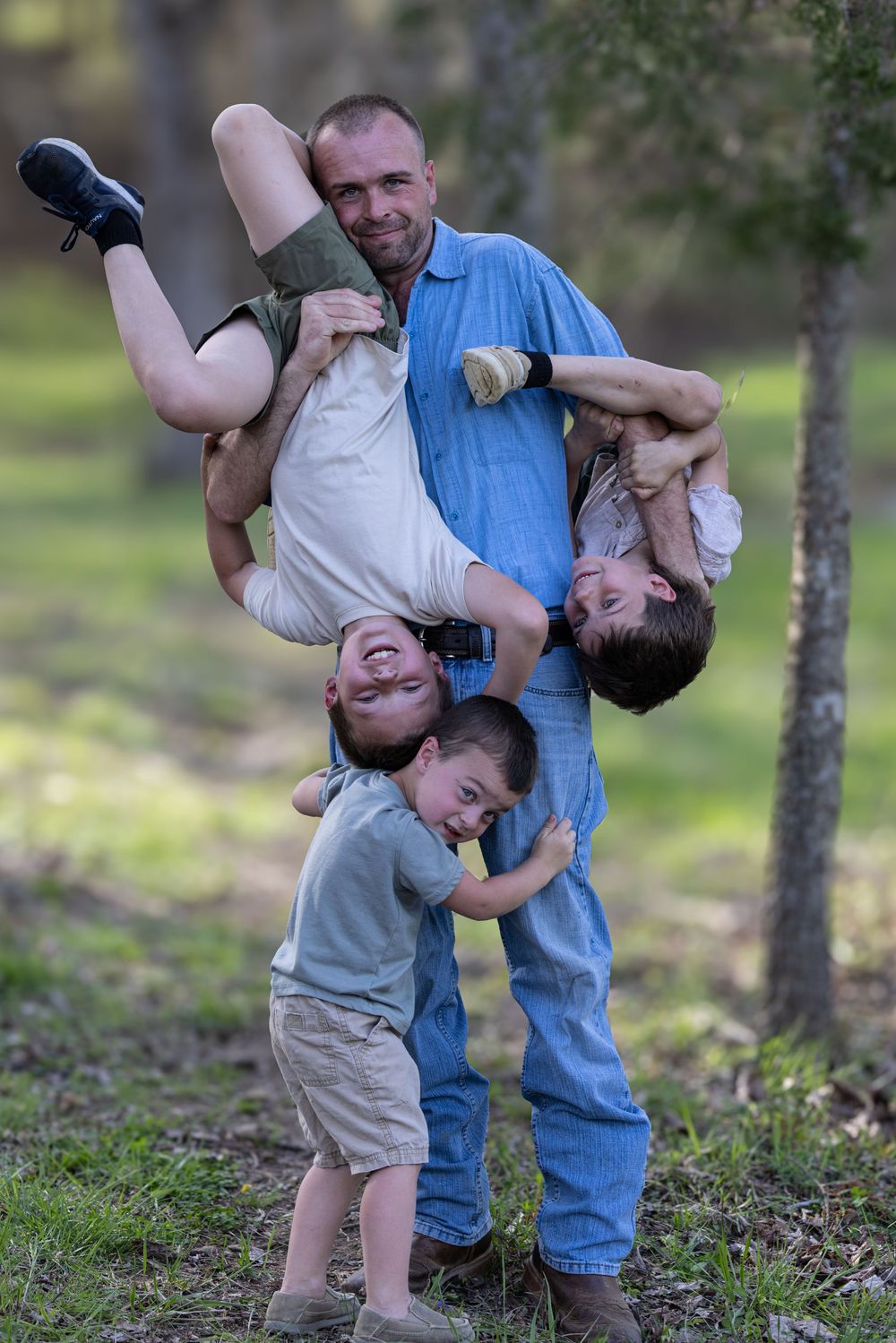 A sequence of playful moments shows a child being held upside down and swung in a grassy outdoor setting.
