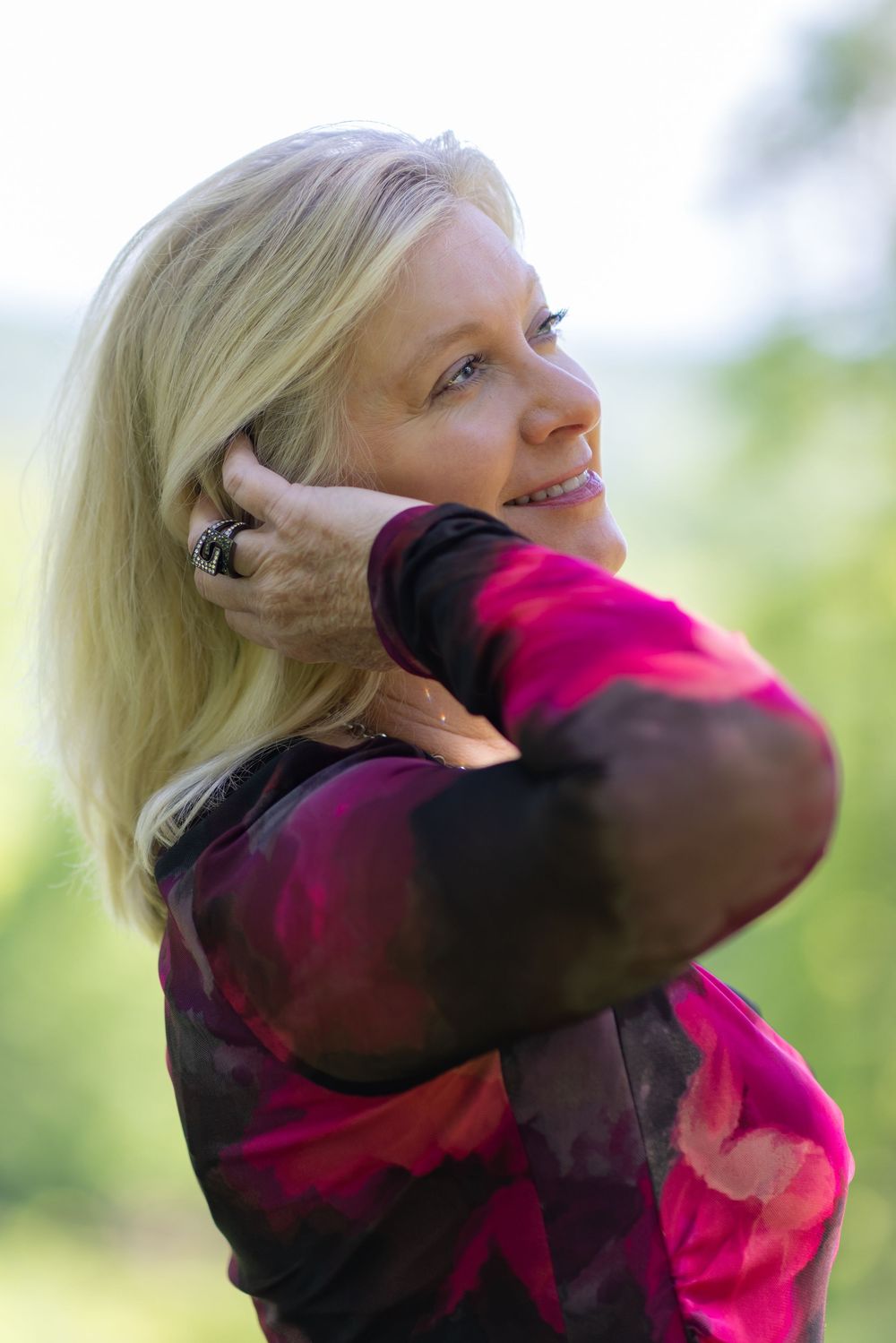 A sequence of dance movement poses in pink and black clothing against a soft bokeh nature background.