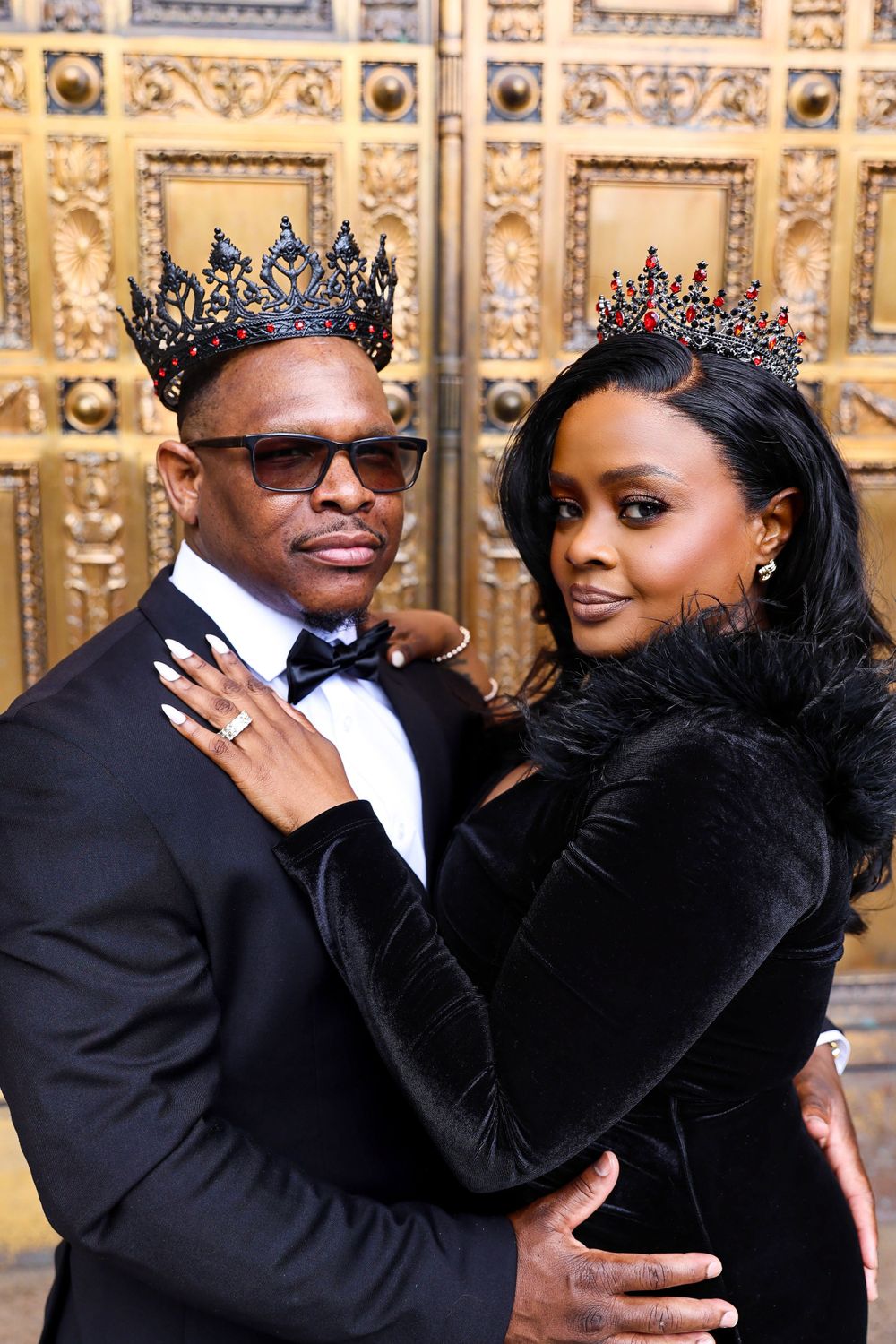A formal couple wearing crowns pose against an ornate golden background.