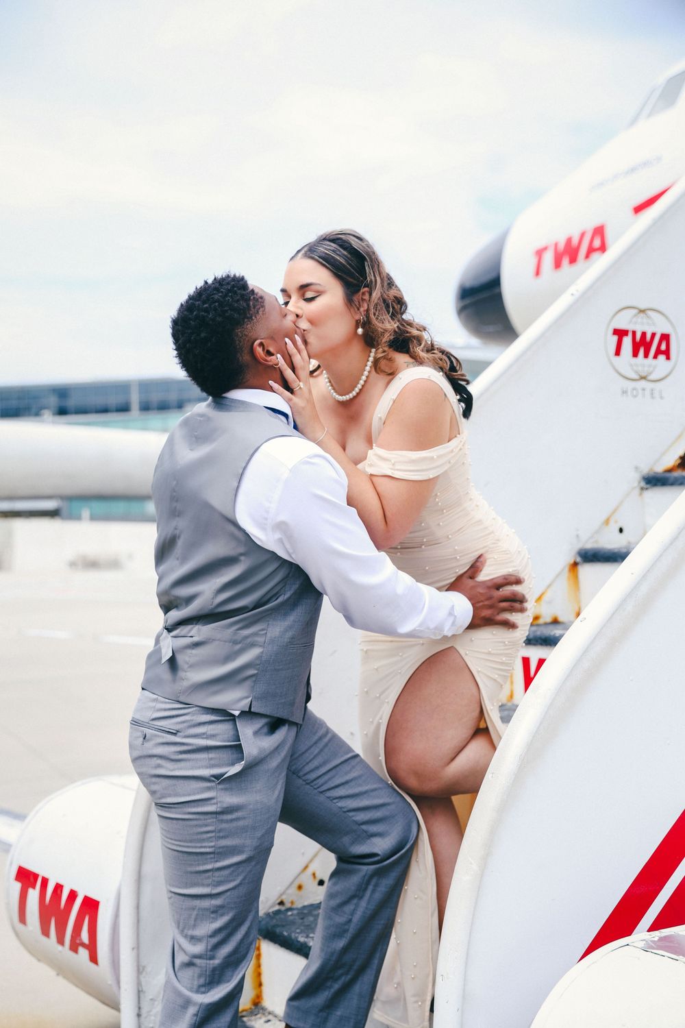 Romantic couple shares intimate moments near a vintage TWA aircraft.