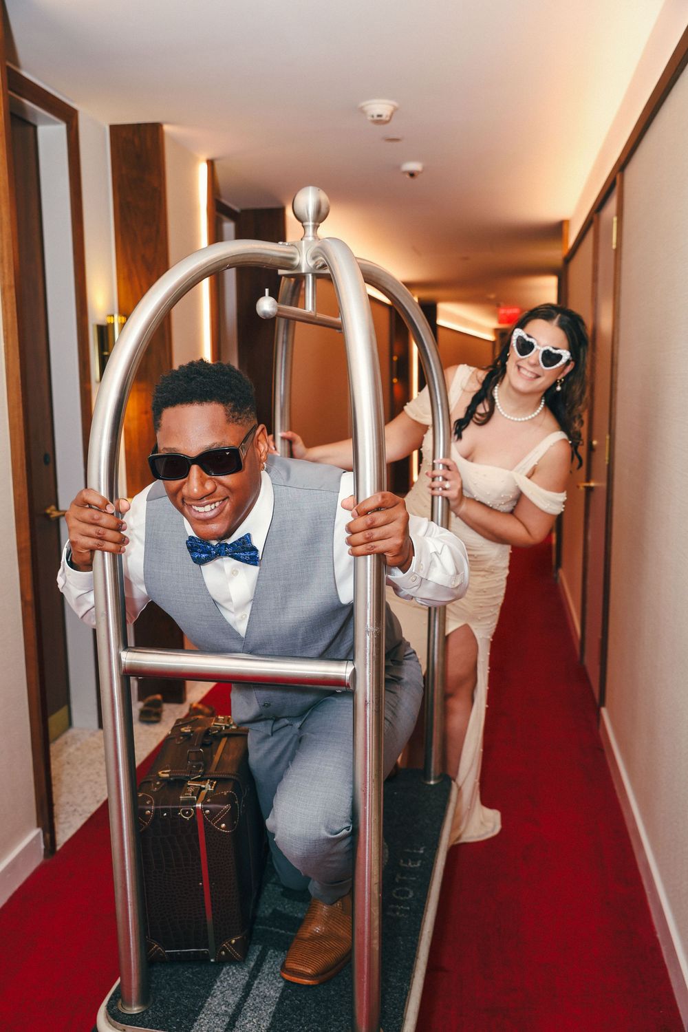 Fun candid moments in a hotel hallway with sunglasses and red carpet.